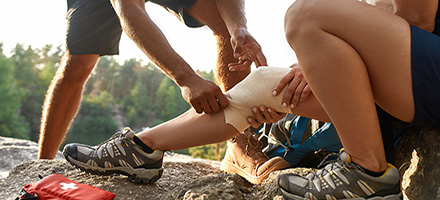 Man helping hiker bandage injured knee.